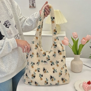 Close-up of soft beige plush tote bag featuring blue floral patterns and brand label