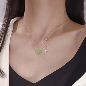 Close-up of green Hetian jade Ping'an buckle pendant on a gold necklace worn by a model