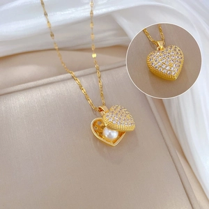 Golden heart locket necklace with white pearl and pave crystals on silk background