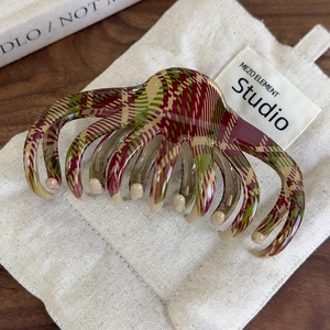 Gros plan d'une pince à cheveux à carreaux rouges et verts sur un sac en tissu rustique