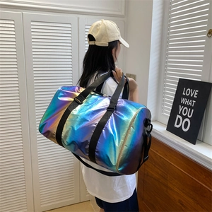 Holographic gradient travel duffel bag with black straps worn by a model in bright room