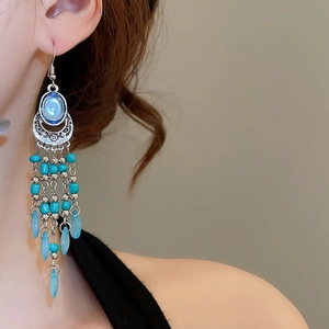 Close-up of bohemian tassel earrings with sky blue beads and vintage silver metal details