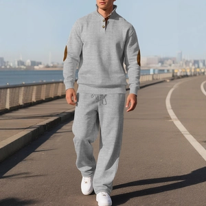 Men's grey vertical knit tracksuit with buttoned collar and brown elbow patches in outdoor setting