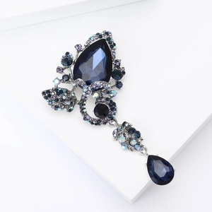 Detail of elegant silver brooch with dark blue pear-shaped gems and teardrop pendant