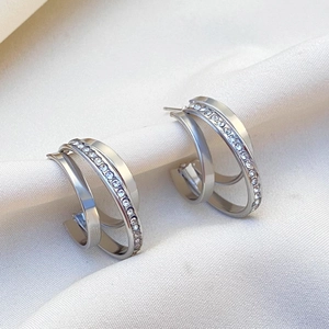 Detail of silver C-shape earrings with triple-layered bands and paved white zircons