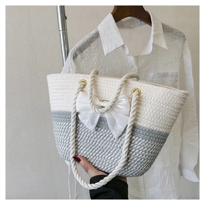 Detail of hand-held woven tote bag in white and grey with large bow and rope handles
