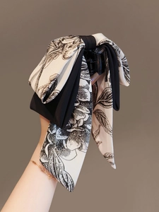 Détail d'une grande pince à cheveux avec nœud et motifs floraux à l'encre noir et blanc