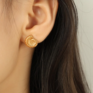 Elegant gold seashell stud earrings with textured spiral design for women on model