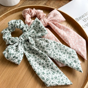 Close-up of floral fabric scrunchies with long ribbons on a wooden tray