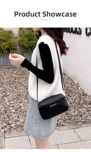Outdoor shot of a woman wearing a black quilted crossbody camera bag with gold logo