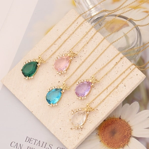 Golden bee necklaces with teardrop gems in five colors on a decorative stone slab