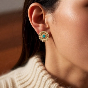 Detailed view of vintage gold sunburst earrings with turquoise stone and white zircons