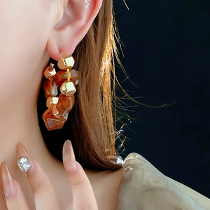 Chic amber resin and gold faceted bead hoop earrings worn by a model in a close-up side view