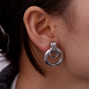 Macro shot of silver nested double hoop earrings on model highlighting metallic texture