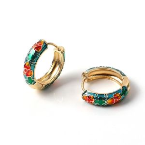 Detailed macro shot of vintage gold hoops with colorful floral enamel and clover patterns