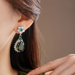 Macro shot of a drop-shaped green gemstone earring with sparkling white stone pavé