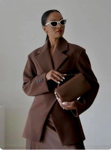 Dettaglio di un blazer marrone in lana con vestibilità sciancrata e borsa abbinata
