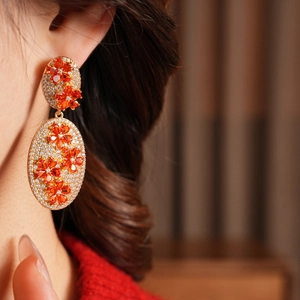Close-up of vintage floral drop earrings with orange petals and sparkling zircon crystals