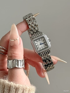 Detail of silver square watch with Roman numerals and crystal bezel worn on wrist