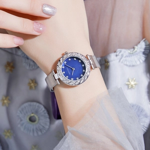 Women's watch with blue dial, rhinestone bezel, and silver mesh band worn by a model