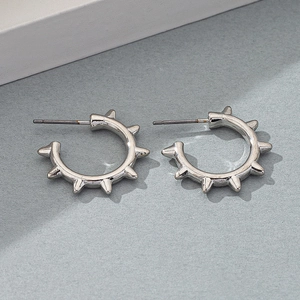 Detail view of silver punk hoop earrings with spike charms on a minimalist grey background