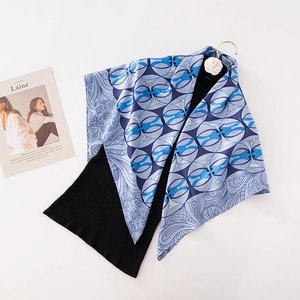 Elegant blue and white geometric print silk scarf layered on a black knit sweater
