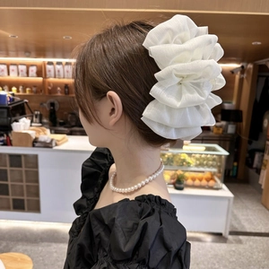 Large white pleated fabric hair claw clip with elegant floral shape on female model