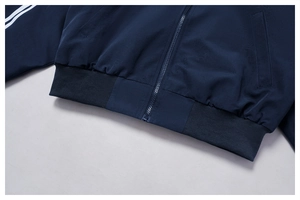 Dettaglio della giacca sportiva blu navy con strisce bianche e orlo elastico a coste
