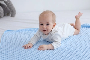 Dettaglio di morbida coperta per neonati azzurra con texture minky a pois in rilievo