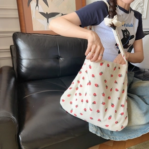 Détail de la texture du sac cabas en velours côtelé imprimé fraises sur canapé