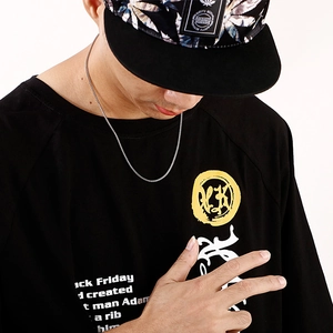 Close-up of a silver stainless steel box chain necklace worn on a black t-shirt