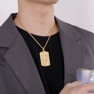 Men's gold titanium necklace with engraved skull and snake square pendant worn by model