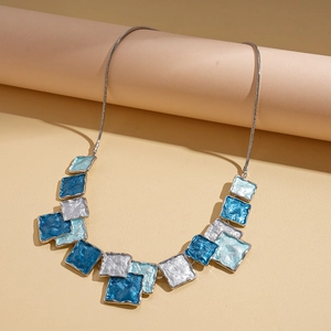 Detail of geometric blue and white enamel pendant on a silver snake chain necklace