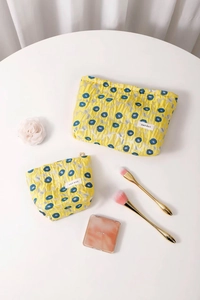 Detail of yellow pleated jacquard cosmetic bags with floral patterns and H&R logo