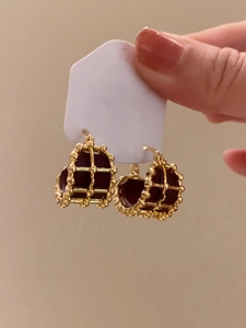 Detail of gold-plated lattice earrings with dark brown leather inlay on display card