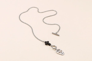 Detail of stainless steel skull pendant with cross charm and OT clasp necklace