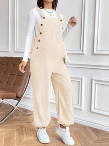 Detail view of apricot corduroy maternity overalls featuring side button and pocket texture