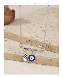 Detail of silver S925 Hamsa Hand and Evil Eye pendant on a safety pin necklace