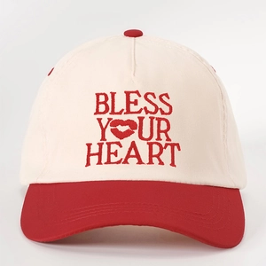 Two-tone beige and red baseball cap featuring BLESS YOUR HEART embroidery design