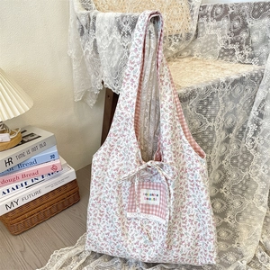Floral canvas tote bag with pink check pocket and bow detail in a cozy setting