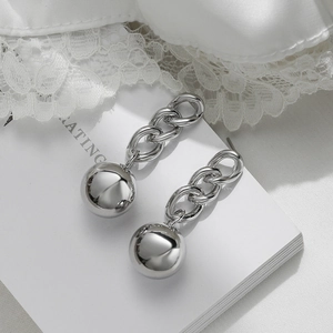 Silver chain drop earrings with polished metallic spheres on elegant silk and lace fabric