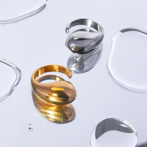 Anelli a goccia lucidi in oro 18K e argento su una superficie d'acqua creativa