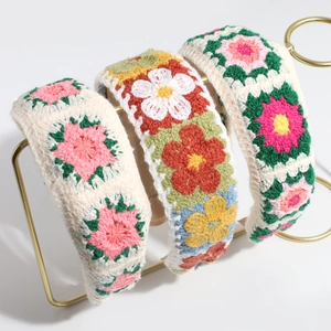 Three sweet knitted floral headbands in pastoral style on a gold display stand