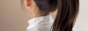 Close-up of minimalist white pearl earring shown on the earlobe for style display