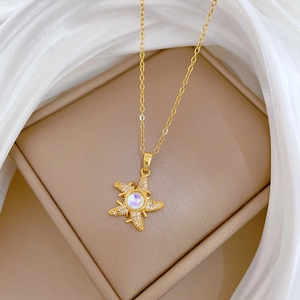 Elegant gold starfish necklace with a central crystal and diamonds on a beige jewelry box