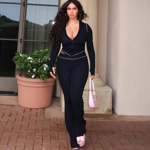 Detailed view of women's black long sleeve top and flare pants set with white contrast stitching