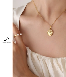 Detail of gold coin necklace and pearl ring in stainless steel worn by model