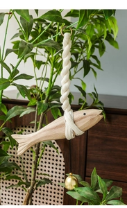 Detail of wooden fish hanging decor with thick cotton rope and small brass bell