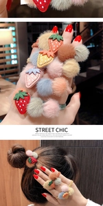Dettaglio di elastici per capelli fragola in peluche colorati su polso e acconciatura