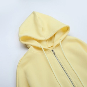 Detail eines hellgelben Zip-Hoodies mit Kordelzug und Metallreißverschluss-Textur